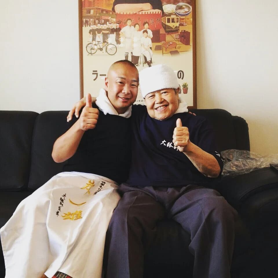 TODO_TRANSLATION — Koji Tashiro and Kazuo Yamagishi seated together with their arms around each other